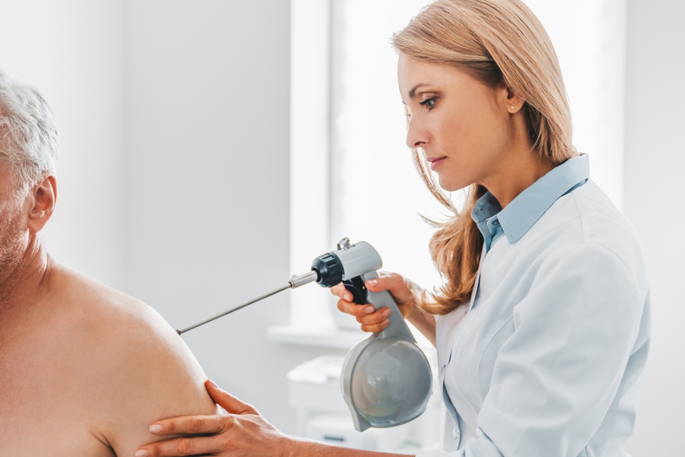 A chiropractor applies cryotherapy to a patient's shoulder using a specialized device - Chiropractor Irving TX A chiropractor applies cryotherapy to a patient's shoulder using a specialized device - Chiropractor Irving TX